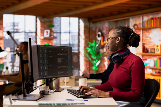 Startup employee using large language model application to get help with coding tasks. Woman interacting with AI LLM chatbot PC GPT software on PC in software development workplace