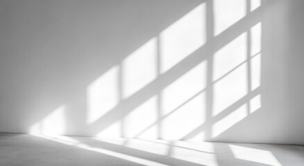 Fototapeta premium Bright sunlight casting geometric shadows of window panes on a plain white wall and smooth floor creating an airy and serene atmosphere
