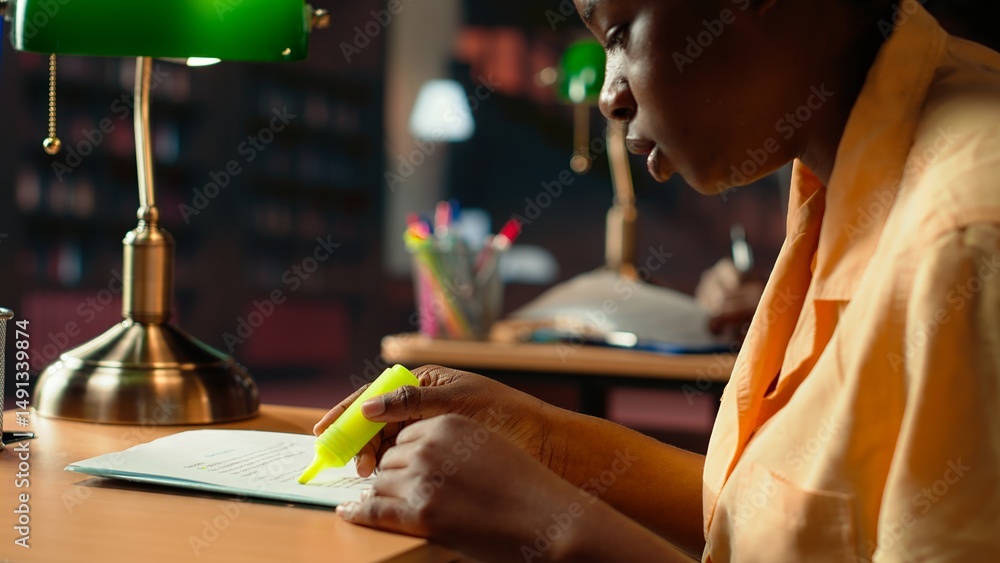 Poster college student underlining relevant phrases from the class notes using a highlighter pen, learning 