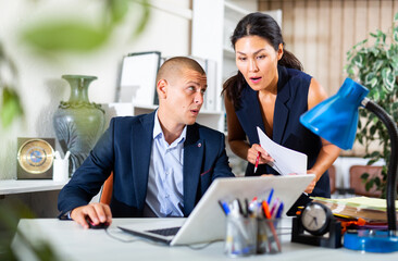 Portrait of two positive business colleagues chatting about work in office