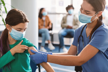 Little Girl Getting Vaccinated Against Covid, Female Doctor Applying Plaster After Giving...