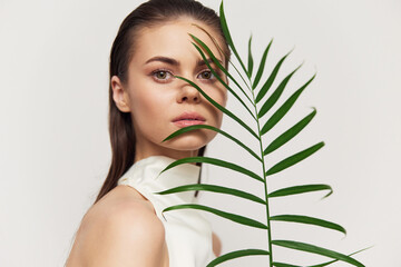 Naklejka premium Elegant young woman with fern in minimalist fashion portrait showcasing natural beauty and tranquility.