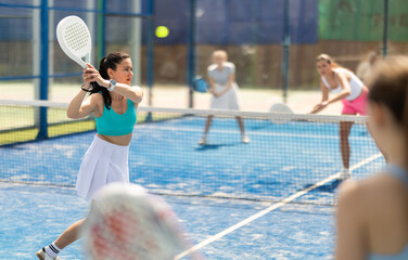 Fototapeta na wymiar Woman playing with other paddle tennis players. Tennis players participate in a tournament and hit balls to get points