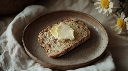 A slice of homemade bread with a generous spread of butter melting on top, set on a rustic plate with a linen napkin for a cozy breakfast vibe.