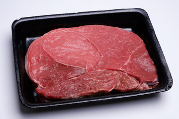 raw fresh beef knuckle steak cut in black tray isolated on white background