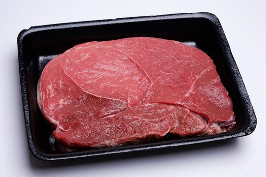 raw fresh beef knuckle steak cut in black tray isolated on white background