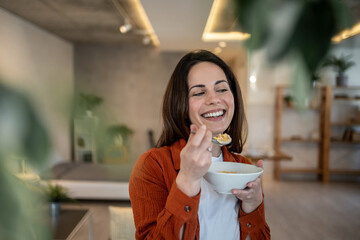 Happy woman enjoying breakfast cereal at home