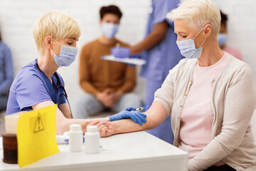Obraz premium Coronavirus Vaccination. Senior Lady Receiving Covid-19 Vaccine Injection Sitting With Nurse In Clinic Room. Corona Virus Medicine, Treatment And Population Immunization Concept. Selective Focus