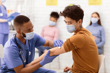 Fototapeta premium Covid-19 Vaccination. Asian Man Receiving Coronavirus Vaccine Intramuscular Injection In Arm During Doctor's Appointment In Hospital. Corona Virus Immunization, Protection, Medicine Treatment Concept