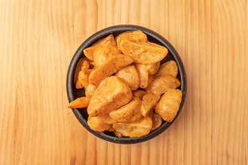 Patatas bravas are served hot as a tapa or appetizer, accompanied by a glass of wine or beer
