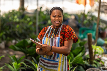 Portrait of successful African woman small business owner into horticulture standing in her garden...