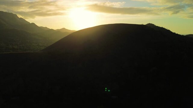 Early morning sunrise behind dark hills near Mount Tapyas in Coron with strong backlight golden sky and tropical mountain silhouettes in Palawan