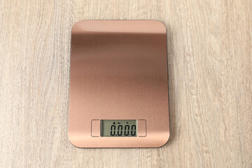 Modern electronic kitchen scale on wooden table, top view