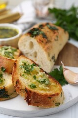 Tasty bread with garlic, herbs and oil on white table, closeup