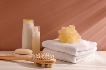 Different bathing products on white table near light brown wall