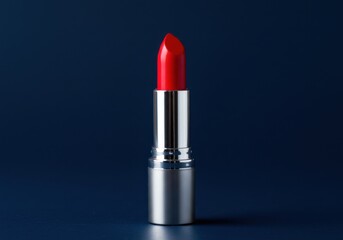 A vibrant scarlet lipstick with a metallic tube against a muted azure ground