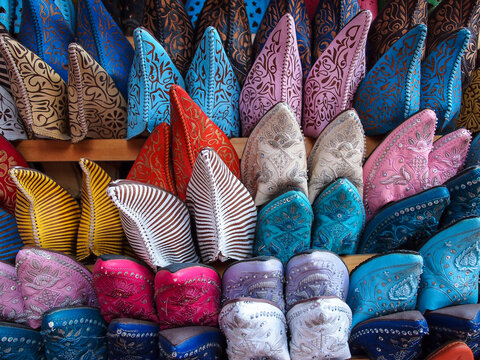 Rows of vibrant handmade traditional slippers in various colors and patterns on display in a market