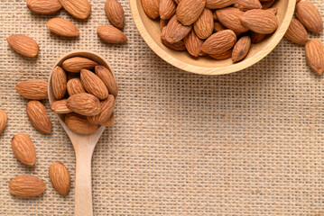 Raw almond nut seed in wooden bowl and spoon with copy space, Top view