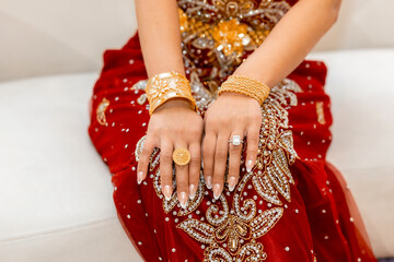 Gold jewelry and ring with diamond on a woman's hands. Woman in ethnic dress, gold bracelets and ring close up. Details of a women's traditional dress with gold patterns in Asian style. Islamic attire