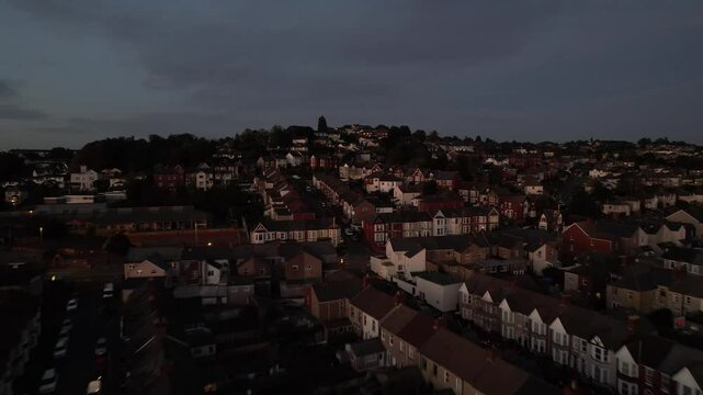 Rows of houses in residential borough. Forwards fly above city at dusk. Town development on hill slope. Newport, Wales, UK