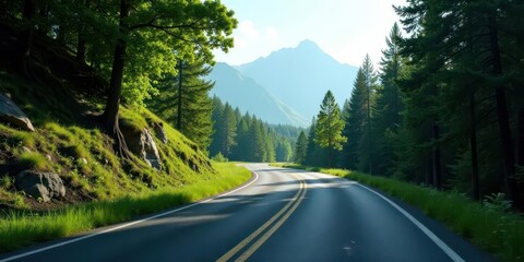 Obraz premium Scenic mountain road winding through a lush green forest landscape on a bright sunny day, offering a tranquil and breathtaking view