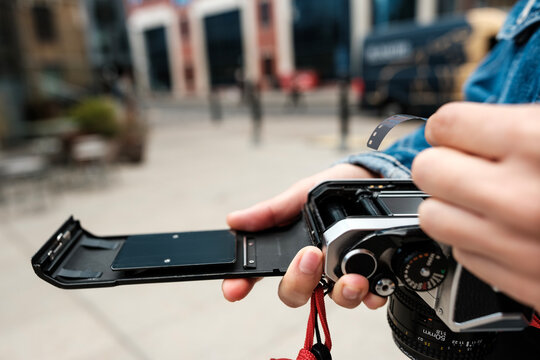 Photographer loading film into vintage analog camera in urban setting