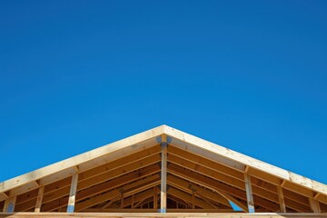 A wooden roof frame against a clear blue sky
