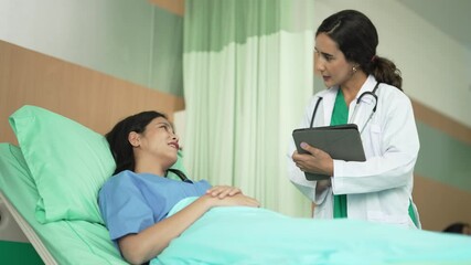 Female doctor using digital tablet to consult with hospital patient in bed, highlighting compassionate healthcare, advanced technology, and professional communication in a clinical environment.