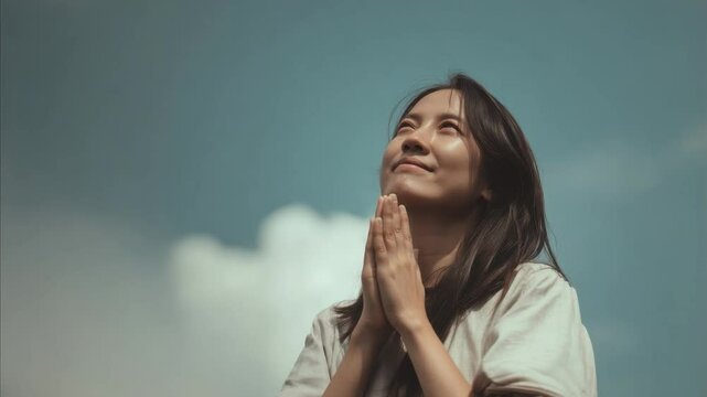 A woman is praying in the sky with her hands together