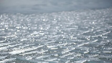 Close up of sheet ice floating on a winter lake surface, sparkling under sunlight, creating a cold, textured landscape of fractured ice fragments. - Powered by Adobe