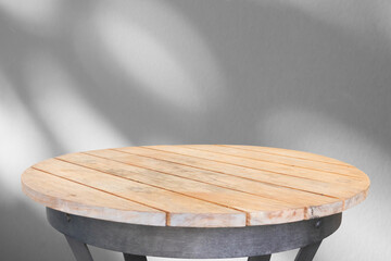 Round wood table top with tree leaves shadow drop on white wall background for mockup product display