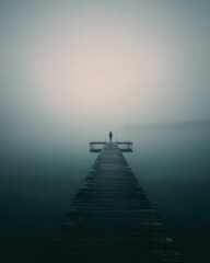 Obraz premium Solitary Figure Standing on Pier in Foggy Lake Landscape Perspective View Serene Mood Wooden Dock Water Horizon Mystery