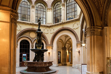 Obraz premium Vienna – View of the Ferstel Passage fountain, the elegant Renaissance Revival bronze sculpture surrounded by the arcade's ornate ironwork and glass-domed ceiling, creating a jewel-like centerpiece.