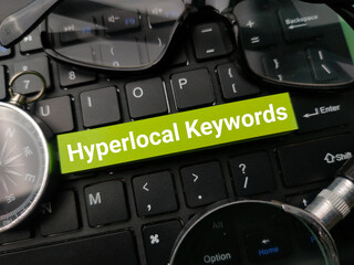Compass and glasses with the word Hyperlocal Keywords on a black keyboard background