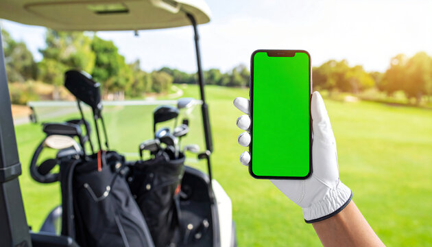 A golfer holds a green screen smartphone in a golf cart with a scenic course view, perfect for app or product mockups. - Powered by Adobe