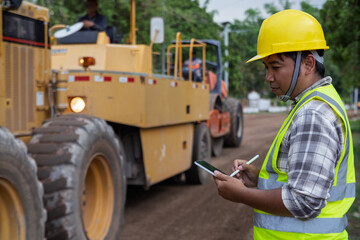 A construction worker checks machinery for safety and performance on an active construction site. Realistic, professional, and suitable for industrial themes.