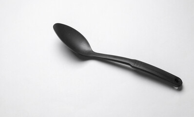 Black plastic kitchen spoon on white background