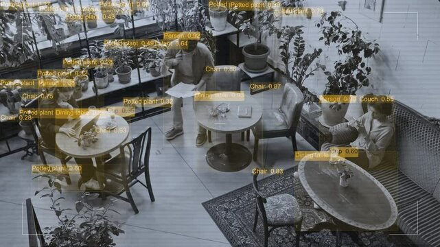 Wide top view with video effects of security camera observing and analyzing busy customers working at tables in coworking cafe. Man with documents talking on smartphone, woman typing on laptop