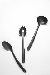 Black plastic kitchen tools on white background. Top view. Flat lay