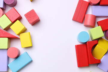 Obraz premium Multicolored wooden children's toy cubes of different shapes on a white background. Copy space