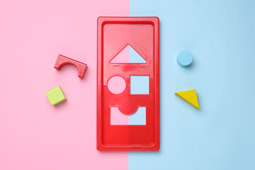 Educational toy sorter for a baby with colored geometric figures on pink blue background