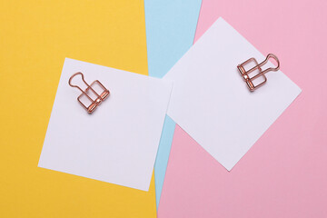 Memo white square sheets of paper with binder clips on colored background. Stationery, education,...