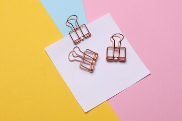 Memo white square sheet of paper with binder clips on colored background. Stationery, education,...