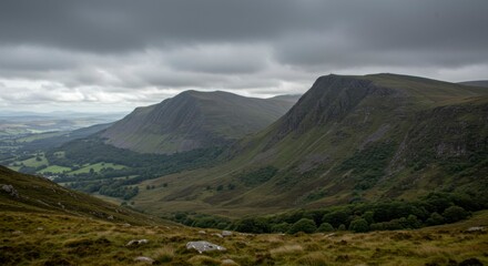 Fototapeta premium Mountain valley vista. Lush greenery, rugged peaks, dark clouds