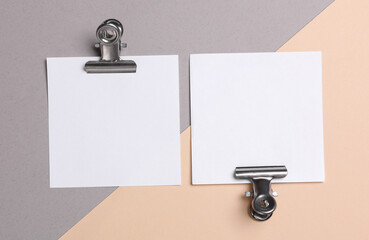 Memo white square sheets of paper with binder clips on pastel background. Stationery, education,...