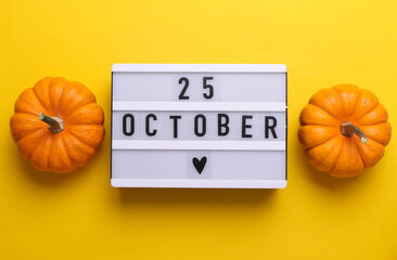 25 october letterboard text on LED Lightbox with pumpkins, yellow background. Seasonal calendar....