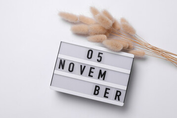 5 november letterboard text on Lightbox with dry lagurus flowers, white background. Seasonal...
