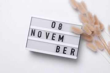 8 november letterboard text on Lightbox with dry lagurus flowers, white background. Seasonal...