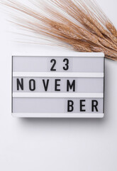 23 november letterboard text on Lightbox with dry wheat, white background. Seasonal calendar. Flat...