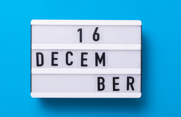 Lightbox with text December 06 on blue backgroung with decorative plant. Flat lay. Top view